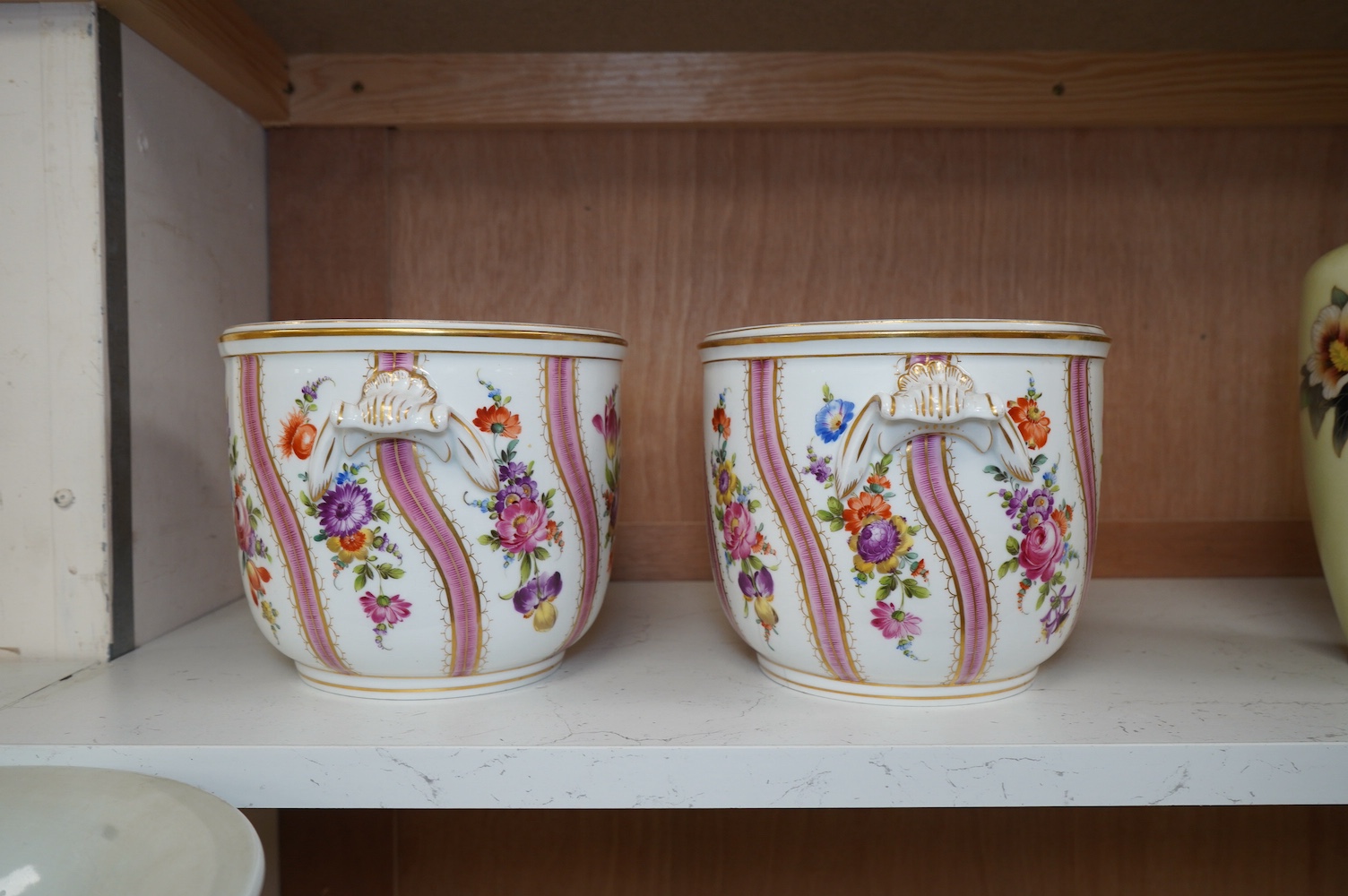 A pair of Dresden wine coolers with floral decoration, 15cm high, 18cm diameter. Condition poor to fair, cracks to the base of one.